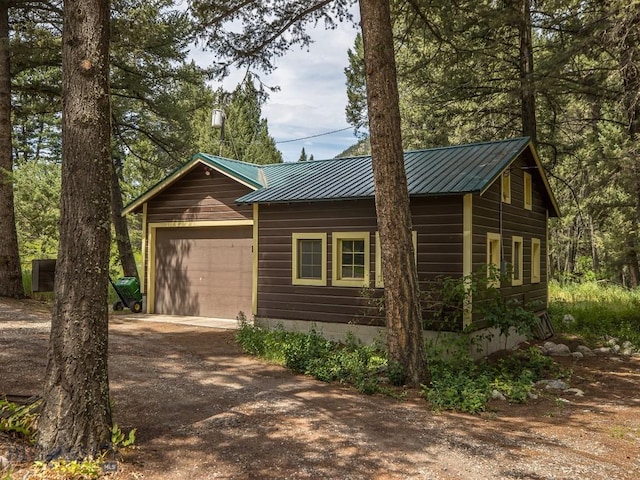 64370 Gallatin Rd, Gallatin Gateway, MT 59730 - rustic home featuring driveway, a metal roof, and an attached garage