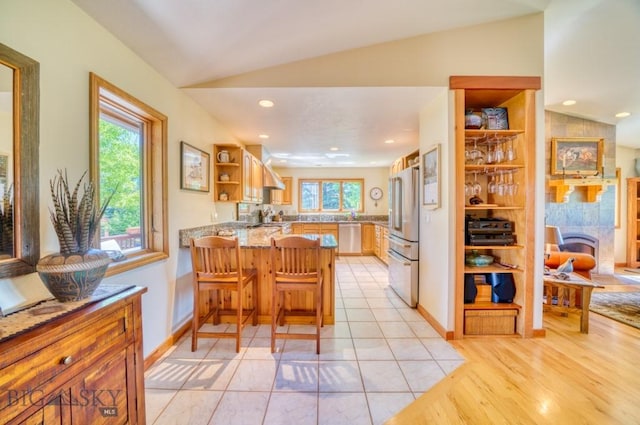 886 Wierda Way, Manhattan, MT 59741 - kitchen featuring open shelves, a peninsula, stainless steel appliances, vaulted ceiling, and light stone countertops
