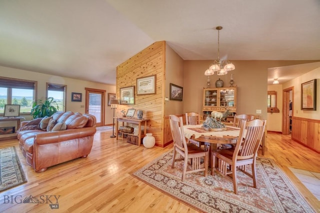 886 Wierda Way, Manhattan, MT 59741 - dining space with a chandelier, light wood-type flooring, lofted ceiling, wood walls, and wainscoting