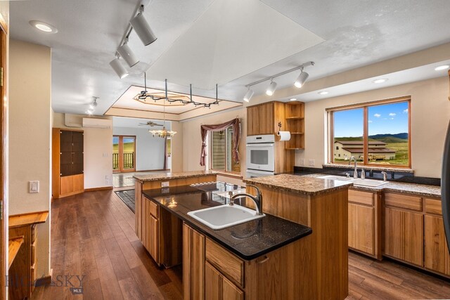 6385 Mt Highway 41, Whitehall, MT 59759 - kitchen featuring a kitchen island with sink, white oven, dark wood-type flooring, rail lighting, and open shelves