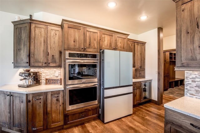 8 Sunset Ct, Ennis, MT 59729 - kitchen featuring double oven, freestanding refrigerator, wine cooler, backsplash, and dark wood-style flooring