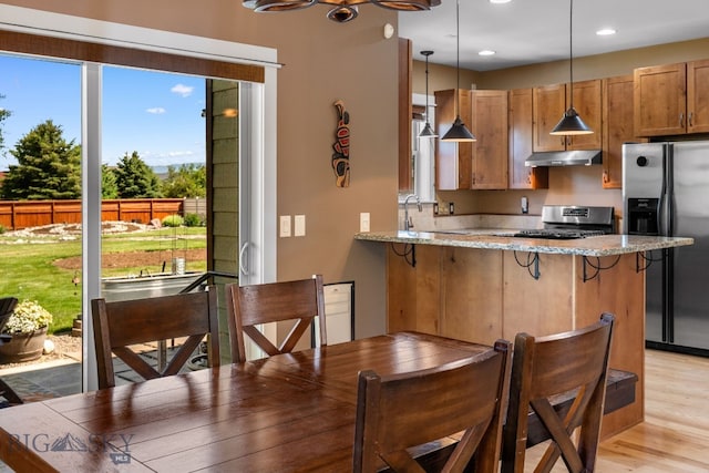 109 Baker St, Belgrade, MT 59714 - kitchen with appliances with stainless steel finishes, under cabinet range hood, light stone counters, a peninsula, and recessed lighting