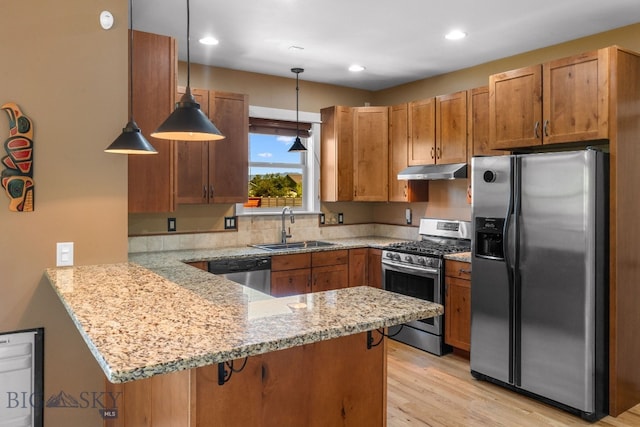 109 Baker St, Belgrade, MT 59714 - kitchen featuring appliances with stainless steel finishes, under cabinet range hood, a peninsula, light wood-style floors, and light stone counters