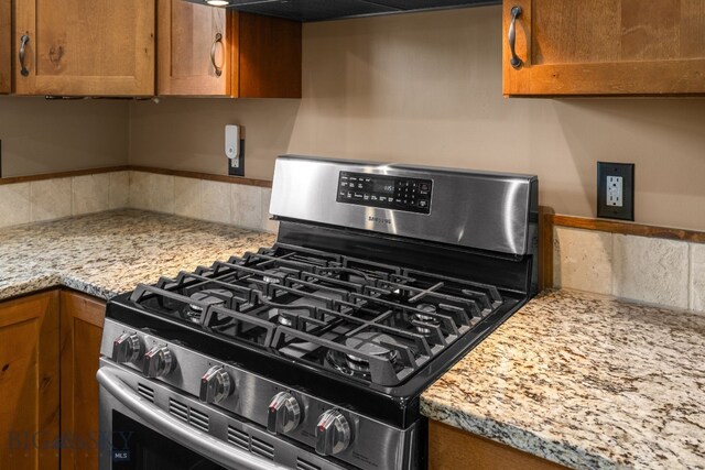 109 Baker St, Belgrade, MT 59714 - kitchen view of gas range, backsplash, brown cabinets, and extractor fan
