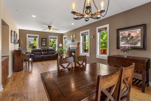 109 Baker St, Belgrade, MT 59714 - dining area with light wood finished floors, a chandelier, a lit fireplace, recessed lighting, and ceiling fan