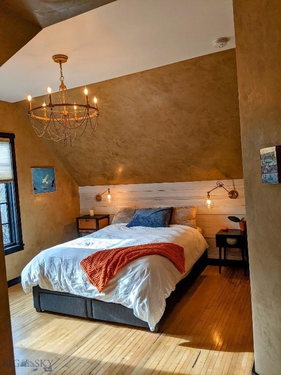 401 S Bozeman Ave, Bozeman, MT 59715 - bedroom with lofted ceiling, hardwood / wood-style flooring, a chandelier, and wooden walls
