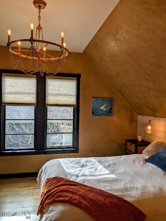401 S Bozeman Ave, Bozeman, MT 59715 - bedroom featuring a chandelier, vaulted ceiling, multiple windows, and wood finished floors