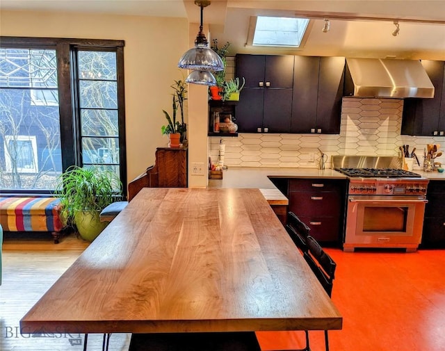401 S Bozeman Ave, Bozeman, MT 59715 - kitchen with stainless steel stove, wall chimney exhaust hood, tasteful backsplash, a skylight, and decorative light fixtures