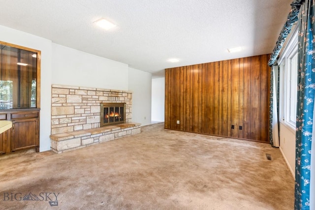 117 Henderson St, Bozeman, MT 59715 - unfurnished living room featuring carpet floors, a textured ceiling, and a stone fireplace