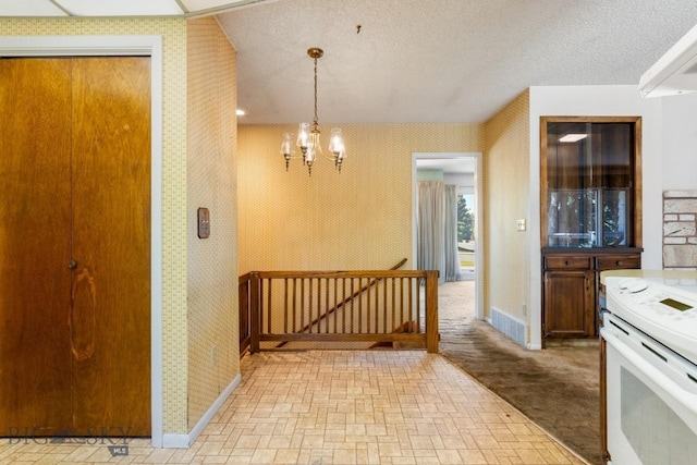 117 Henderson St, Bozeman, MT 59715 - kitchen featuring white electric range oven, wallpapered walls, a chandelier, brick patterned flooring, and decorative light fixtures