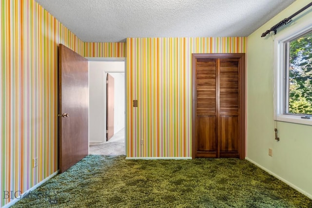 117 Henderson St, Bozeman, MT 59715 - unfurnished bedroom featuring a closet, wallpapered walls, a textured ceiling, and carpet floors