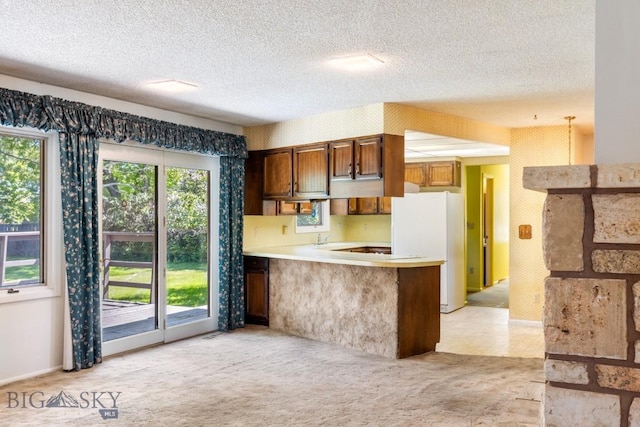 117 Henderson St, Bozeman, MT 59715 - kitchen featuring freestanding refrigerator, a peninsula, a textured ceiling, light countertops, and light colored carpet