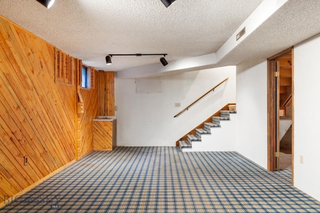117 Henderson St, Bozeman, MT 59715 - finished basement with carpet floors, wooden walls, stairs, a textured ceiling, and track lighting