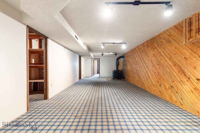 117 Henderson St, Bozeman, MT 59715 - finished basement with wood walls, carpet floors, a wood stove, track lighting, and a textured ceiling