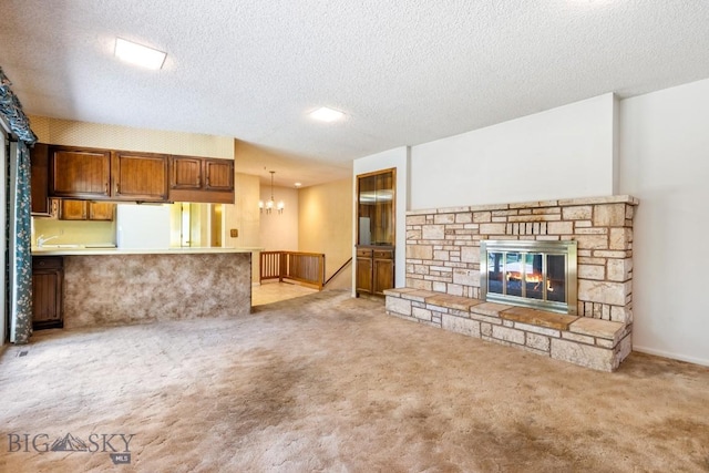 117 Henderson St, Bozeman, MT 59715 - unfurnished living room featuring carpet floors, a fireplace, a textured ceiling, and a chandelier