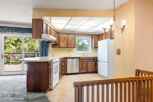 117 Henderson St, Bozeman, MT 59715 - kitchen featuring white appliances, light countertops, wallpapered walls, a peninsula, and brown cabinetry