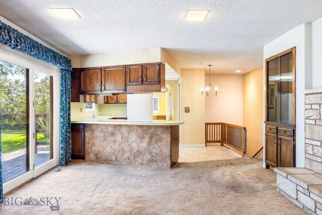 117 Henderson St, Bozeman, MT 59715 - kitchen featuring a chandelier, light carpet, a textured ceiling, a peninsula, and light countertops