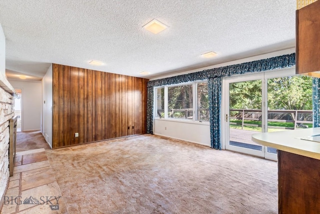 117 Henderson St, Bozeman, MT 59715 - unfurnished living room with a textured ceiling, a stone fireplace, and wooden walls