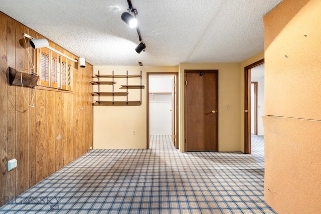 117 Henderson St, Bozeman, MT 59715 - unfurnished bedroom featuring wood walls, a textured ceiling, carpet, rail lighting, and a closet