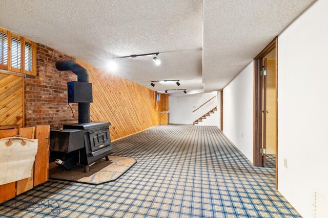 117 Henderson St, Bozeman, MT 59715 - hallway featuring wooden walls, carpet floors, a textured ceiling, track lighting, and stairs