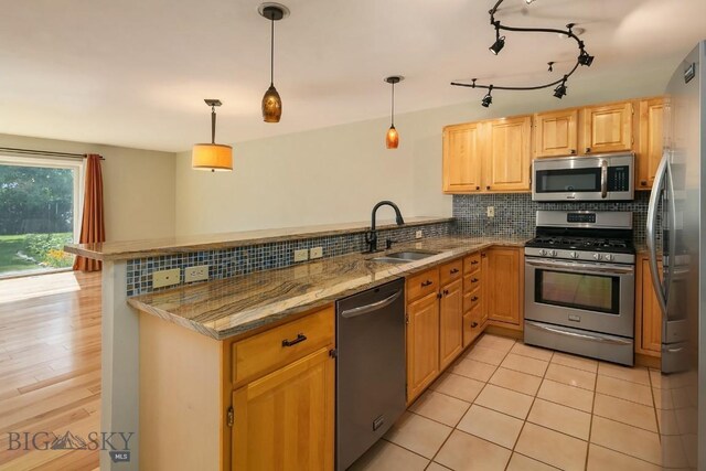 104 S Yellowstone Ave Unit 1, Bozeman, MT 59718 - kitchen with appliances with stainless steel finishes, a peninsula, tasteful backsplash, light stone counters, and decorative light fixtures