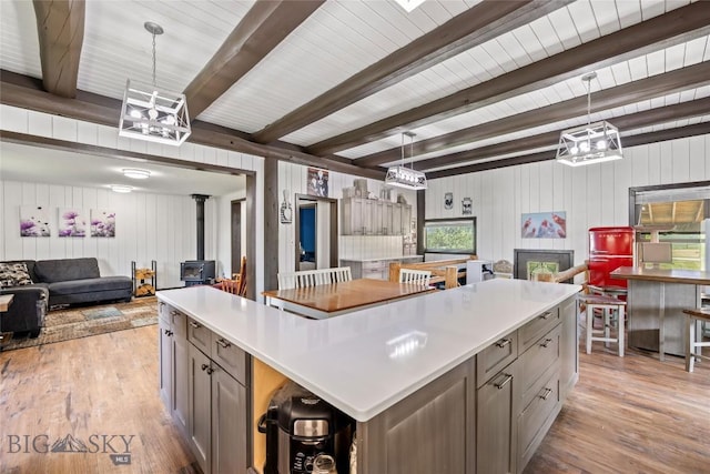 3573 Spain Bridge Rd, Belgrade, MT 59714 - kitchen with open floor plan, a wood stove, light wood finished floors, a chandelier, and beamed ceiling