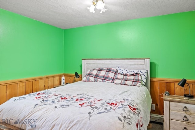 3573 Spain Bridge Rd, Belgrade, MT 59714 - carpeted bedroom with a baseboard heating unit, a wainscoted wall, a textured ceiling, and wood walls