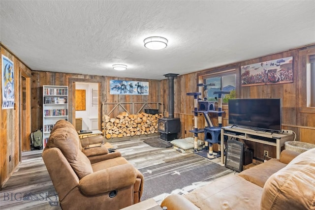 3573 Spain Bridge Rd, Belgrade, MT 59714 - living room with wood walls, a wood stove, a textured ceiling, and wood finished floors