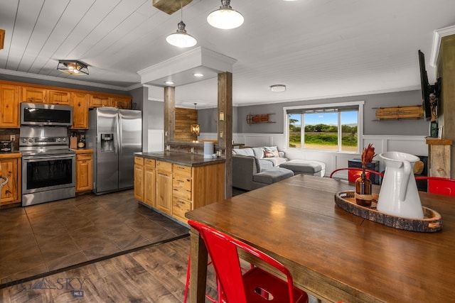 24151 Frontage Rd, Bozeman, MT 59718 - kitchen featuring stainless steel appliances, ornate columns, dark countertops, a wainscoted wall, and crown molding