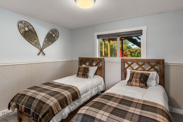 24151 Frontage Rd, Bozeman, MT 59718 - bedroom featuring wainscoting, a textured ceiling, and wood finished floors