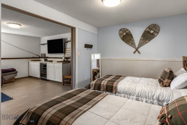 24151 Frontage Rd, Bozeman, MT 59718 - bedroom with wine cooler, wood finished floors, a textured ceiling, bar, and a wainscoted wall