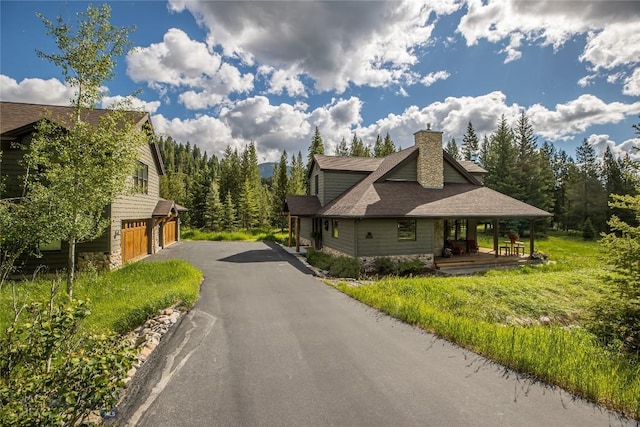 1255 Andesite Rd, Big Sky, MT 59716 - view of side of home with a chimney, asphalt driveway, an attached garage, and a shingled roof