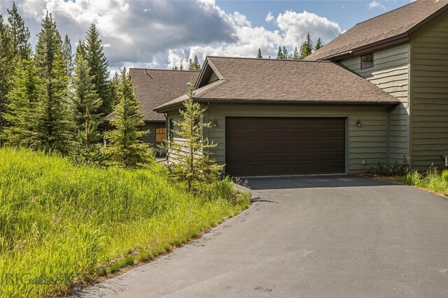 1255 Andesite Rd, Big Sky, MT 59716 - view of side of property with driveway, an attached garage, and roof with shingles