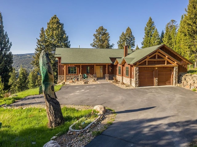 725 Sandhill Rd, Big Sky, MT 59716 - view of front facade featuring stone siding, driveway, a porch, a garage, and a chimney