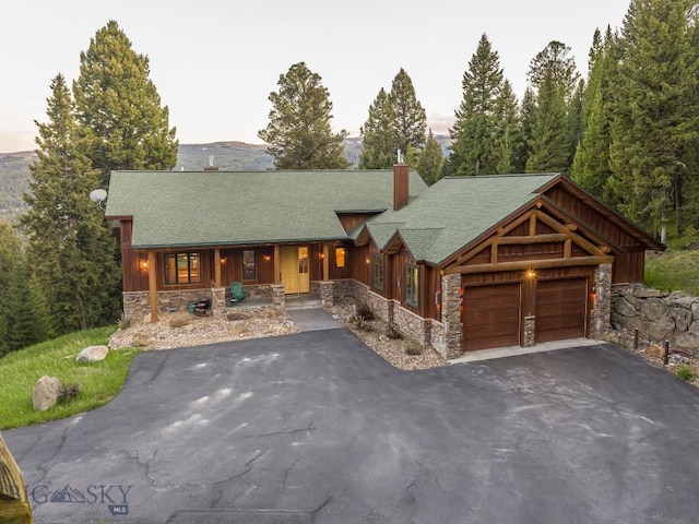 725 Sandhill Rd, Big Sky, MT 59716 - view of front of home with stone siding, covered porch, a chimney, and asphalt driveway