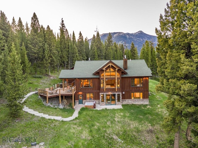725 Sandhill Rd, Big Sky, MT 59716 - back of property featuring a chimney, a patio, a yard, a forest view, and a deck with mountain view