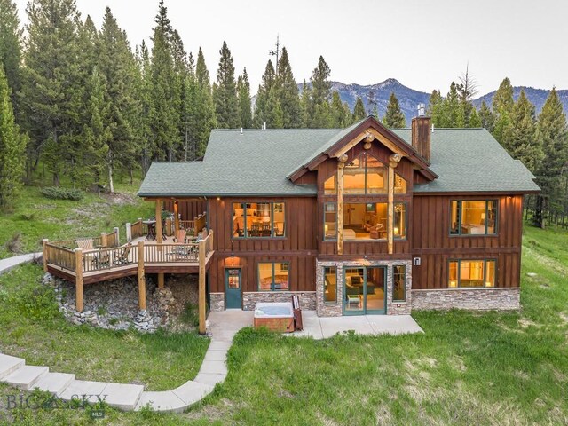 725 Sandhill Rd, Big Sky, MT 59716 - back of house with a patio, a chimney, a deck with mountain view, a lawn, and board and batten siding