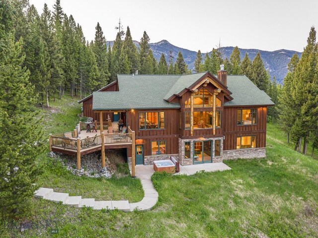 725 Sandhill Rd, Big Sky, MT 59716 - rear view of property with an outdoor hot tub, a chimney, a lawn, and stone siding