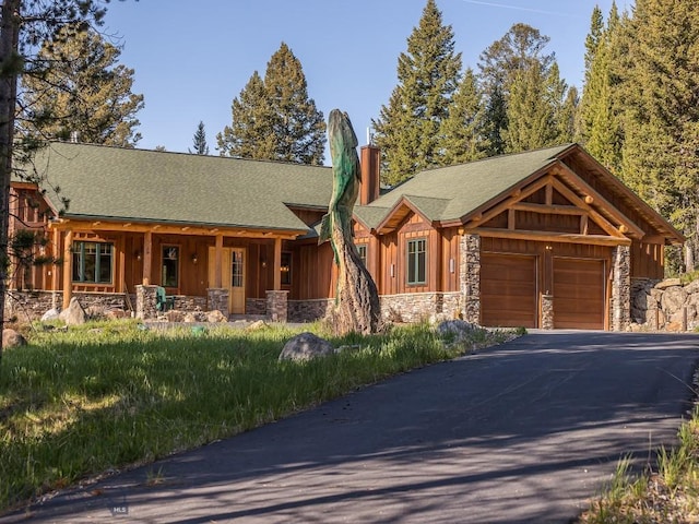 725 Sandhill Rd, Big Sky, MT 59716 - view of front facade with stone siding, an attached garage, a chimney, and board and batten siding