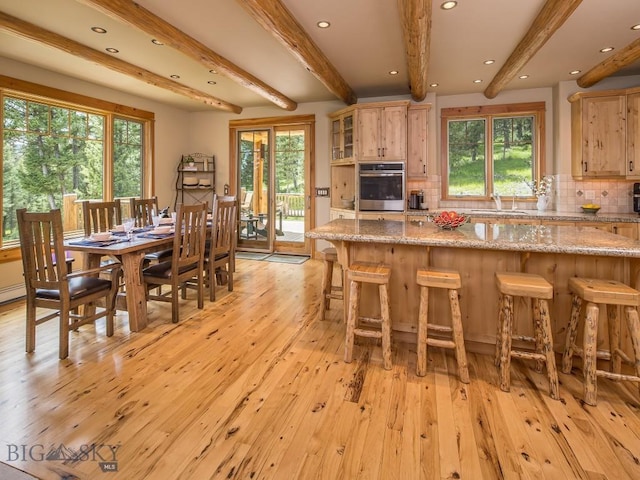 725 Sandhill Rd, Big Sky, MT 59716 - kitchen with oven, beam ceiling, healthy amount of natural light, light wood-style flooring, and tasteful backsplash