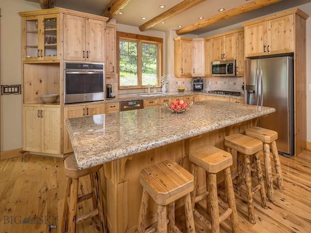 725 Sandhill Rd, Big Sky, MT 59716 - kitchen with appliances with stainless steel finishes, light wood-type flooring, light brown cabinetry, backsplash, and beam ceiling