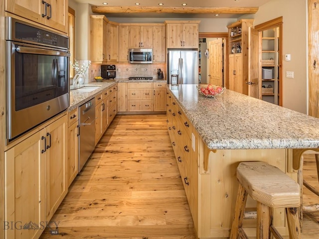 725 Sandhill Rd, Big Sky, MT 59716 - kitchen with stainless steel appliances, light brown cabinetry, recessed lighting, light wood-type flooring, and a kitchen island
