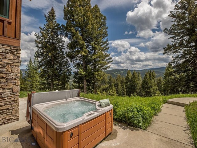 725 Sandhill Rd, Big Sky, MT 59716 - view of patio / terrace with a hot tub, a wooded view, and a mountain view