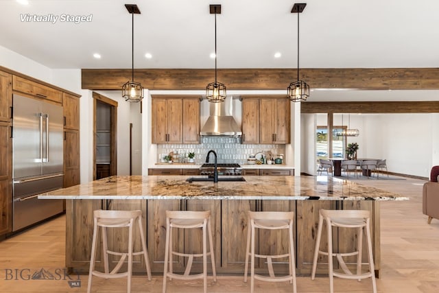 33 Leachman Ln, Bozeman, MT 59718 - kitchen with built in refrigerator, wall chimney exhaust hood, tasteful backsplash, recessed lighting, and a large island with sink