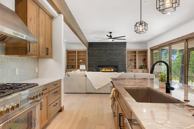 33 Leachman Ln, Bozeman, MT 59718 - kitchen featuring wall chimney range hood, high end stainless steel range oven, ceiling fan, light wood finished floors, and light stone counters