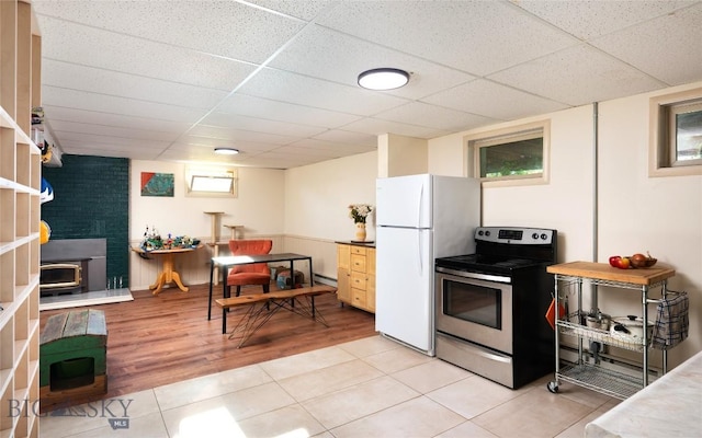 8373 Goldenstein Ln, Bozeman, MT 59715 - kitchen with stainless steel electric range, a wood stove, freestanding refrigerator, a paneled ceiling, and light tile patterned flooring