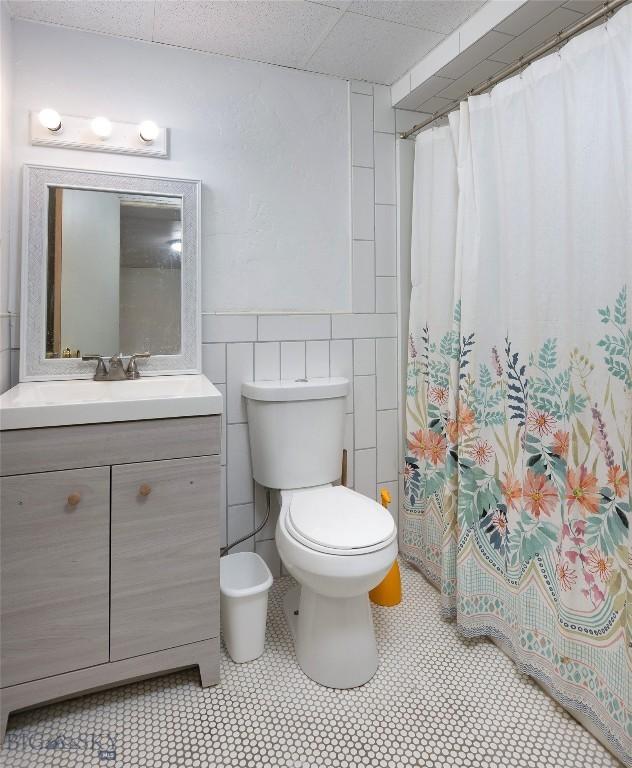 8373 Goldenstein Ln, Bozeman, MT 59715 - bathroom featuring vanity, a shower with curtain, tile walls, and wainscoting