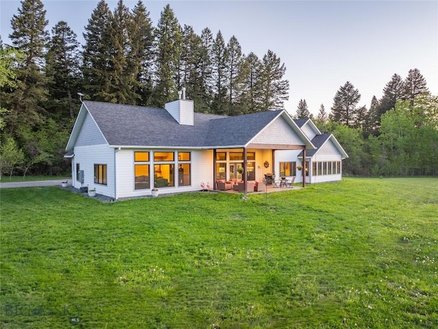 13011 Cottonwood Canyon Rd, Bozeman, MT 59718 - rear view of property featuring a chimney, a lawn, roof with shingles, and a patio area