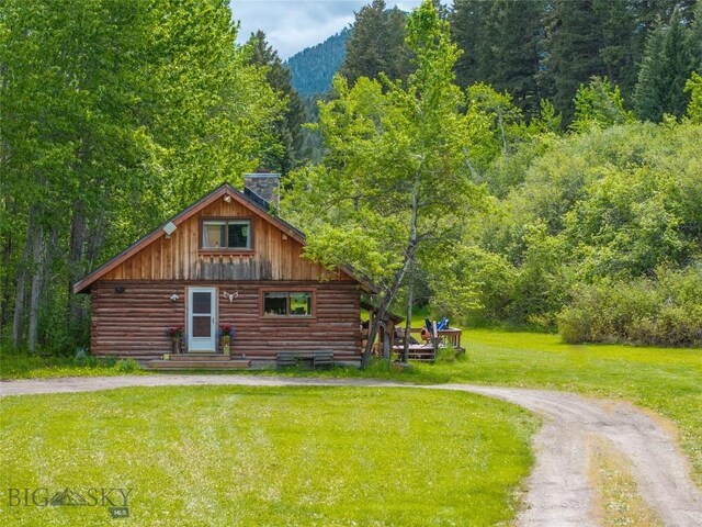 13011 Cottonwood Canyon Rd, Bozeman, MT 59718 - view of home's exterior with log siding, a view of trees, a chimney, a lawn, and dirt driveway