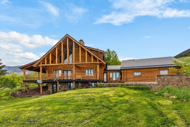 FourBarRanches Corbly Gulch, Belgrade, MT 59714 - back of house with a chimney, a lawn, stone siding, a metal roof, and a wooden deck